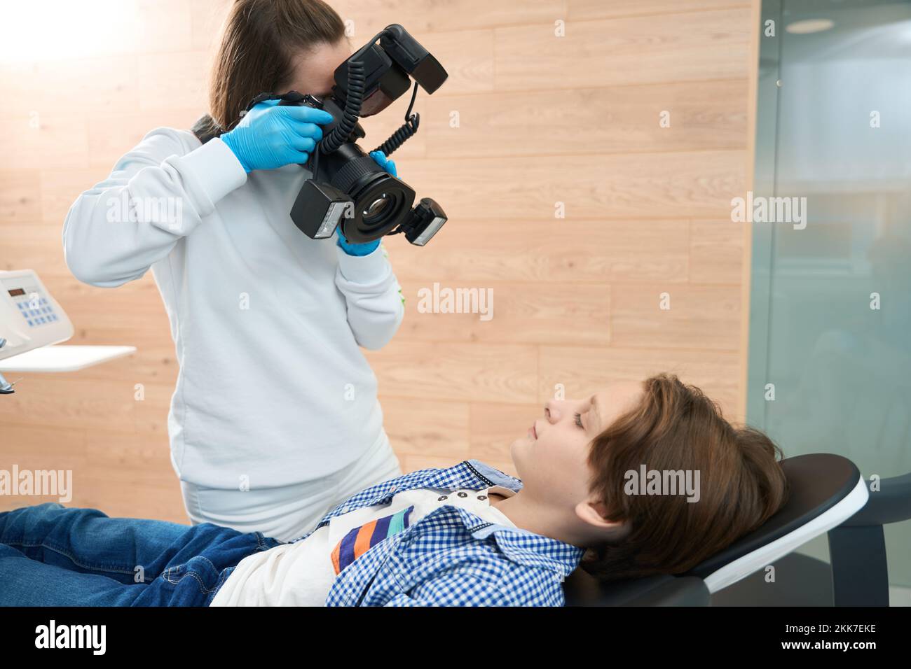 Ragazzo in sedia dentale, dentista donna prende fotografia dentale di lui Foto Stock