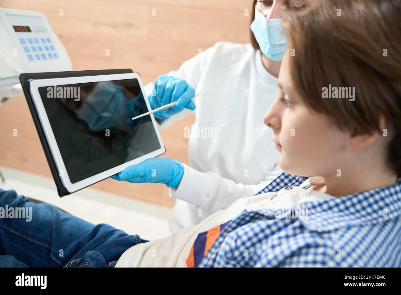 Il dentista della donna consulta un giovane paziente in un dentista Foto Stock