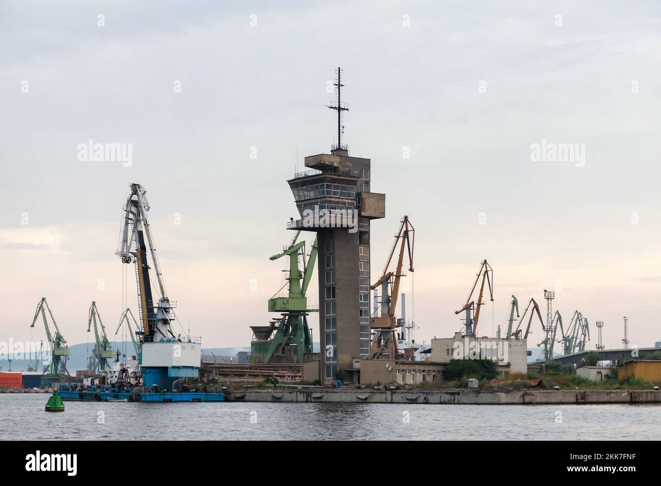 Paesaggio industriale costiero con torre di controllo del traffico marino e gru a portale. Porto di Varna, Bulgaria Foto Stock