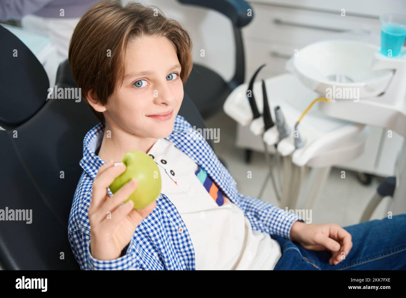 Un ragazzo sorridente si siede su una sedia da dentista Foto Stock