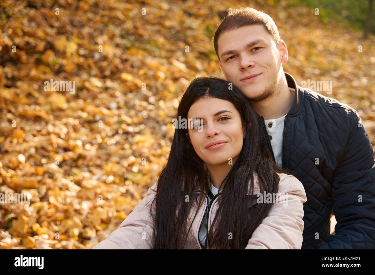 Piacevole coppia riposa tra le foglie gialle cadute Foto Stock