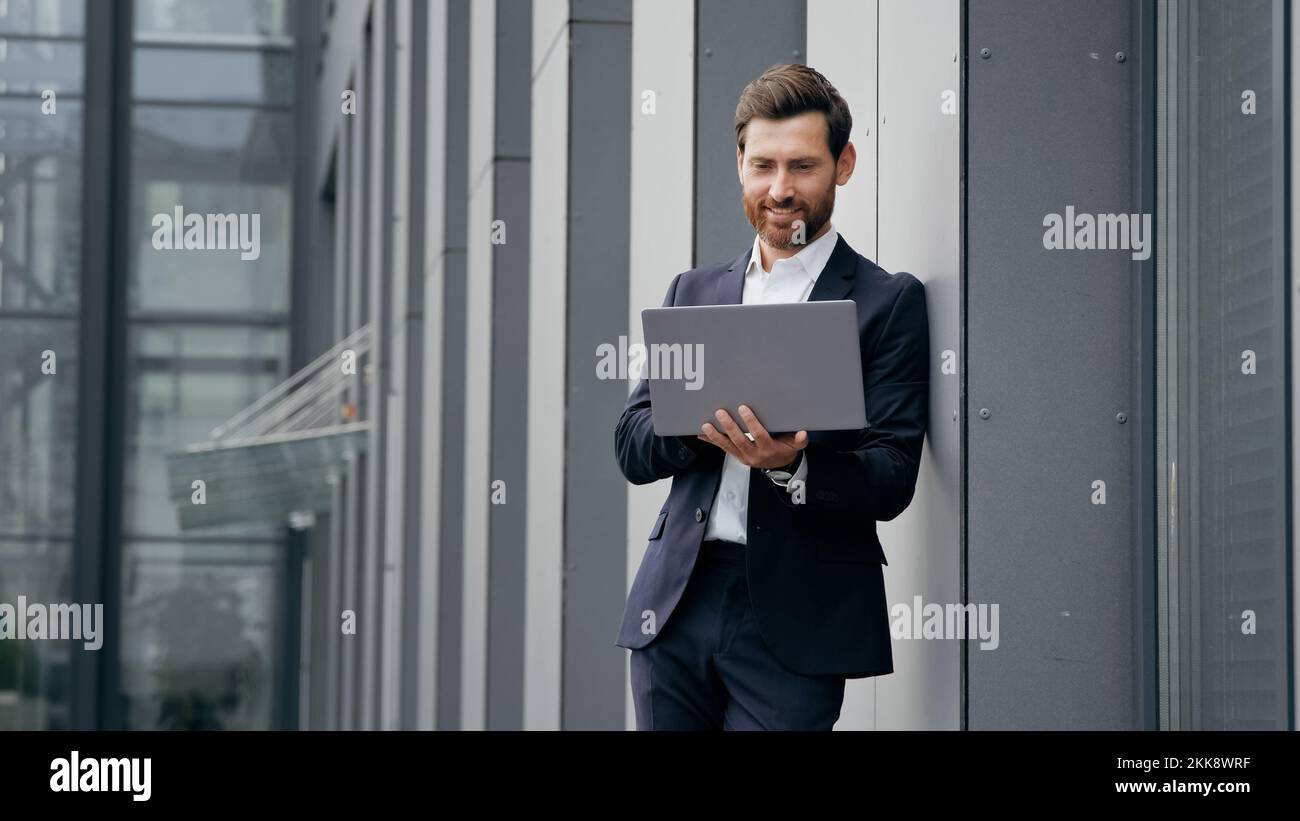 Uomo di successo in piedi in città vicino all'edificio ufficio digitando sul laptop professionista imprenditore architetto designer sviluppa la navigazione online dei progetti Foto Stock