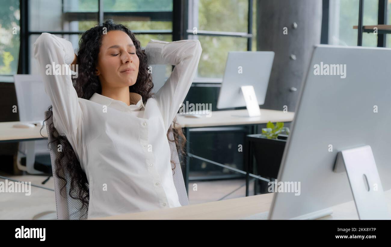 Giovane donna ispanica attraente ufficio manager donna businesswoman digitando sul computer spensierata femminile professionale lavoro finisce si appoggia alla schiena Foto Stock