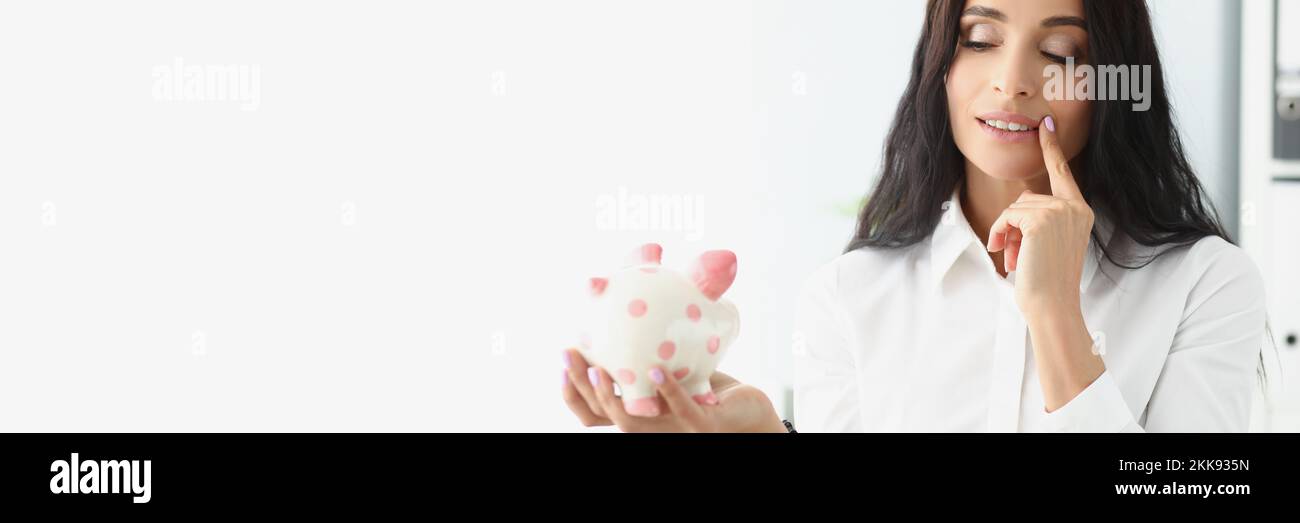 Donna tenere piggybank, pensare al modo migliore di utilizzare i soldi, risparmiare per il futuro Foto Stock
