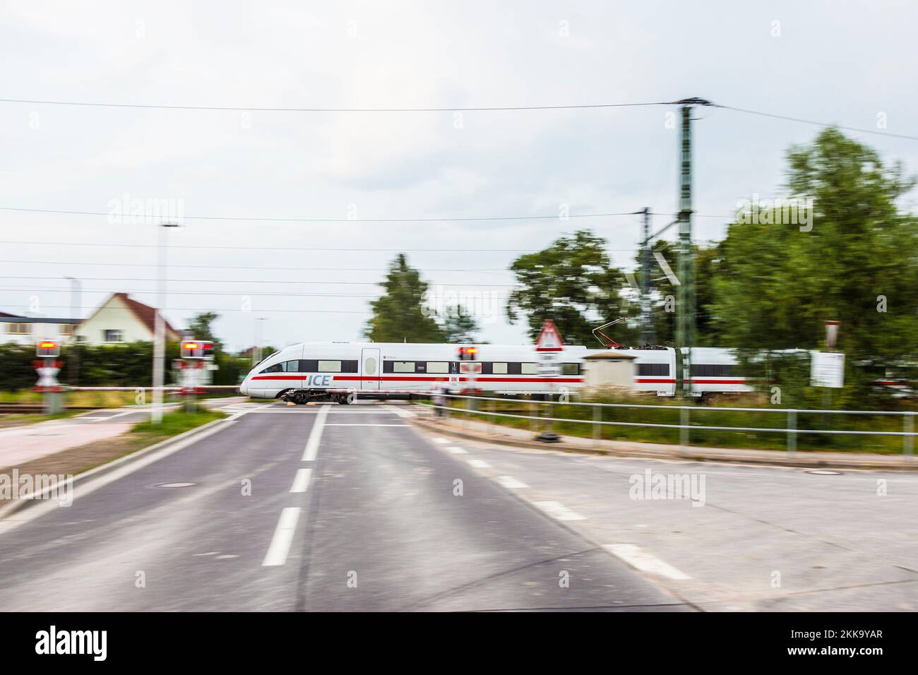 Zuessow, Germania - 4 agosto 2015: Treno ad alta velocità ICE attraversa la strada e un piccolo villaggio di Zussow, Germania. Foto Stock