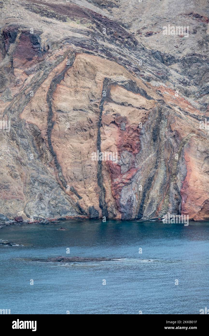 Strati di ciuffo e basalto su un arido pendio di insenatura sull'oceano Atlantico, sparati in una luminosa luce autunnale a Baia d'Abra, Madeira, Portogallo Foto Stock