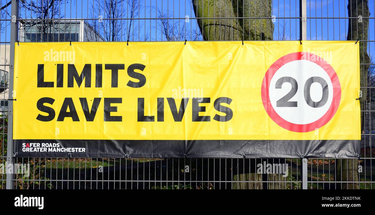 Il banner del limite di velocità dice "Limits Save Lives" (limiti salvare vite) con un suggerimento di 20 miglia all'ora sul recinto di una scuola a Manchester, Regno Unito Foto Stock