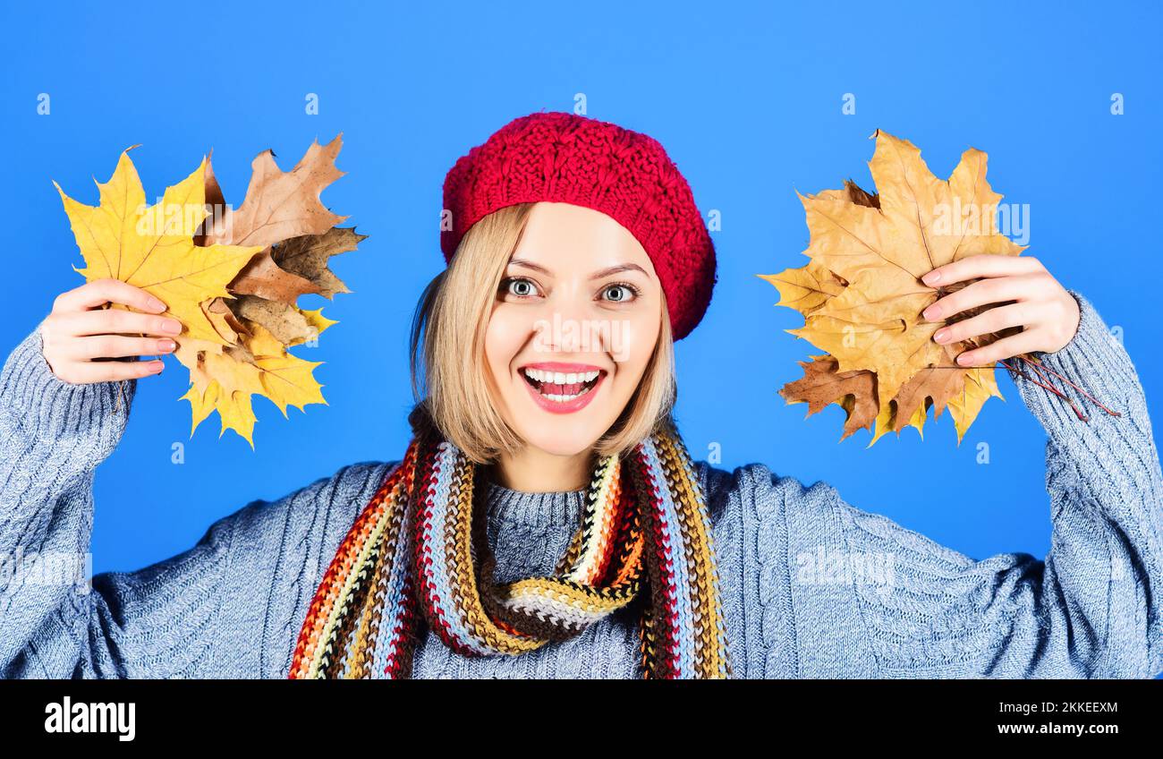 Autunno modella ragazza con foglie di caduta in abiti caldi. Donna in maglia maglione, sciarpa e berretto rosso Foto Stock