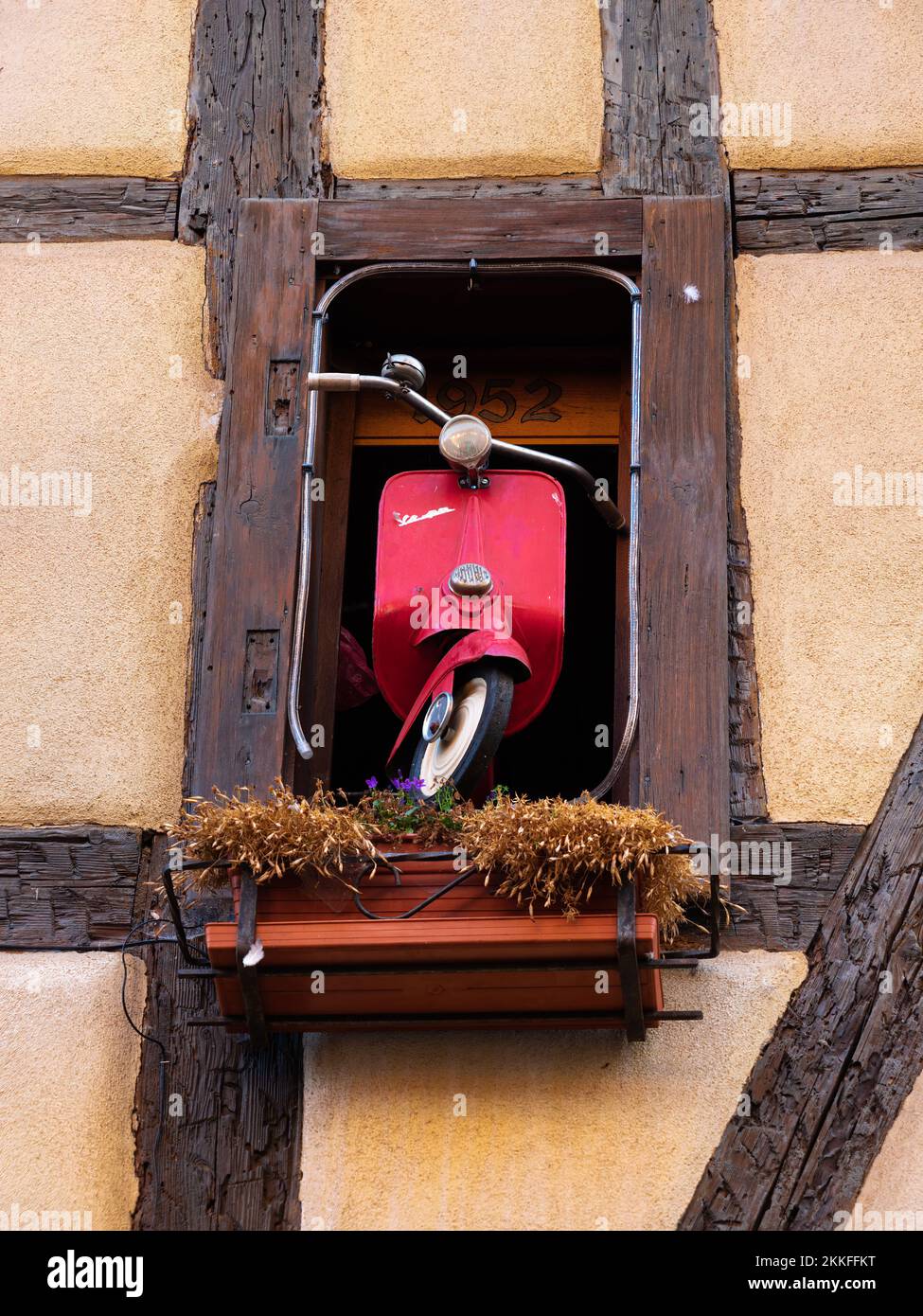 Riquewihr, Francia - 12 ottobre 2022: Vespa Scooter rosso nella finestra di casa tradizionale in Alsazia Foto Stock