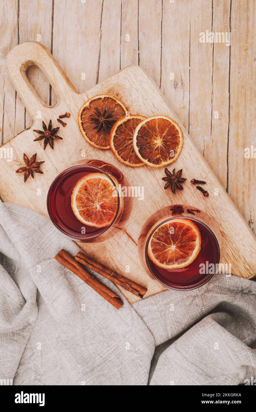 Due bicchieri con VIN brulé sul tagliere di legno con spezie e fette di arancia, vista dall'alto. Foto Stock