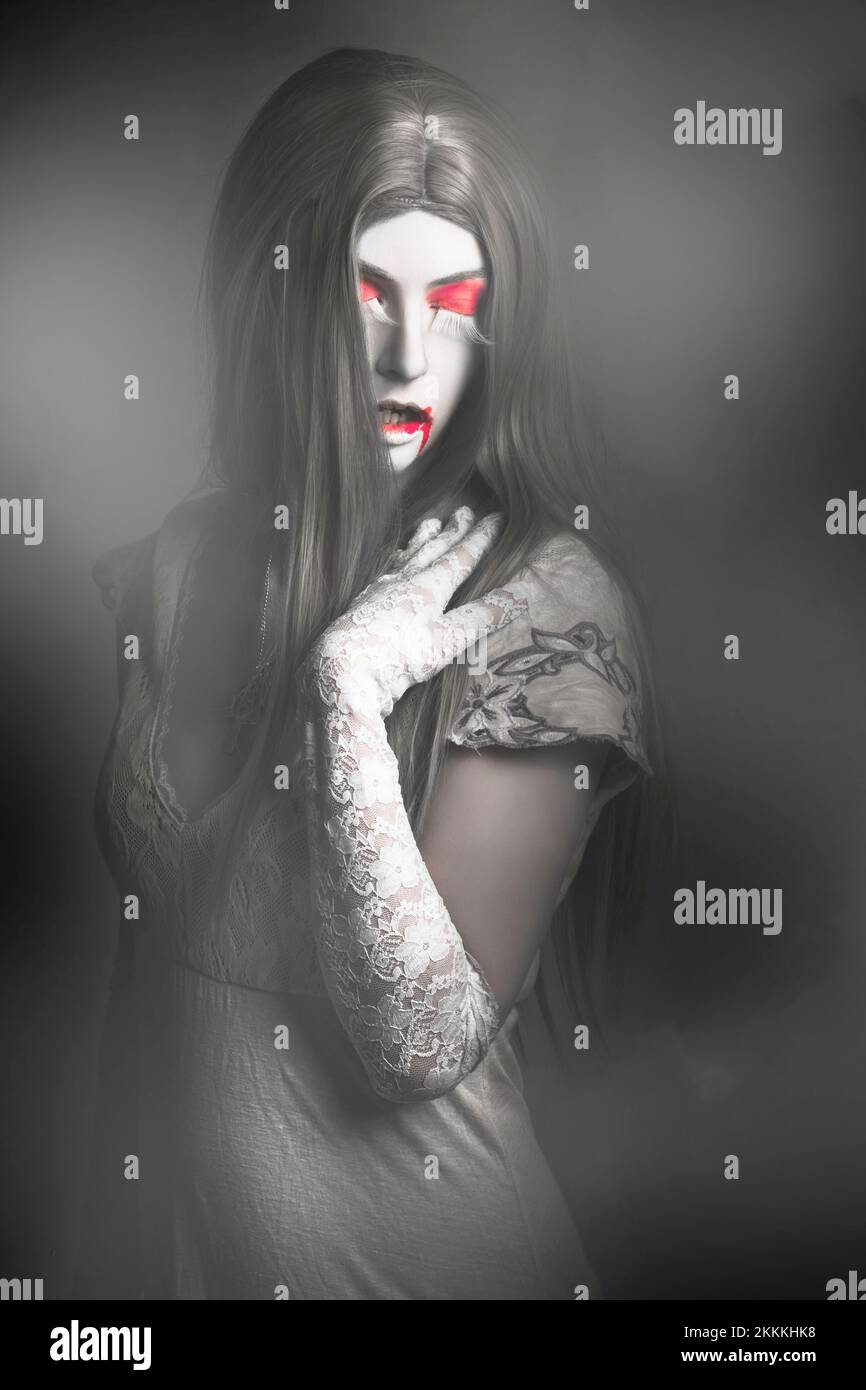 Dark arte ritratto di una bella donna vampiro con lunghi capelli grigi in piedi in una nebbia cimitero di copertura. Twilight incubo Foto Stock