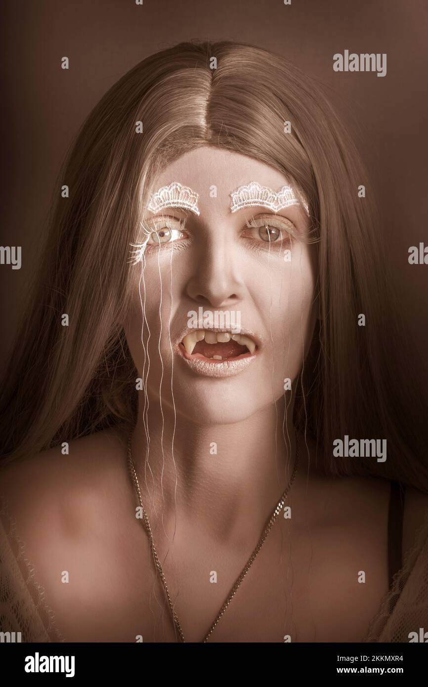 Vintage halloween ritratto di una fantasia gotica vampire girl ululano con fang denti e misterioso specchio Foto Stock