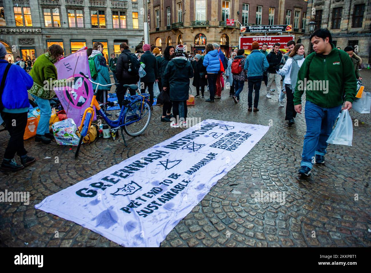 Un uomo guarda un grande banner posto a terra contro il lavaggio del verde nel settore della moda durante la dimostrazione della ribellione estinzione del Black Friday. L'organizzazione climatica, Extinction Rebellion (XR) ha organizzato una dimostrazione contro il consumo eccessivo durante il Black Friday, e per porre fine a questa giornata. Gli attivisti hanno svolto un'azione chiamata Free (ky) Friday in Piazza Dam, dove hanno messo centinaia di vestiti di seconda mano che le persone potrebbero portare per libero o scambiare vestiti. Con questa azione l'organizzazione vuole mettere il profitto al di sopra delle persone e del pianeta e rompere con la cultura dei consumatori Foto Stock