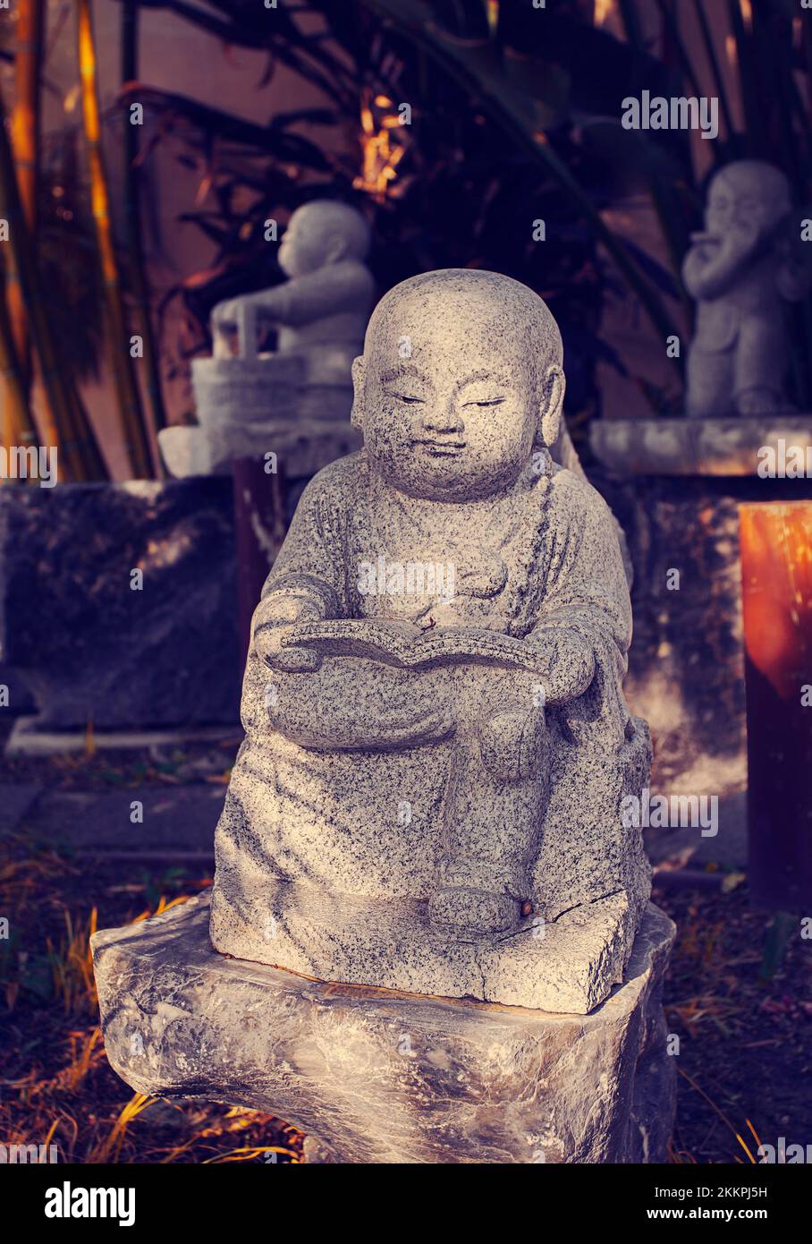 Statua di uno sramanera in possesso di un libro di insegnamento del Buddha Foto Stock