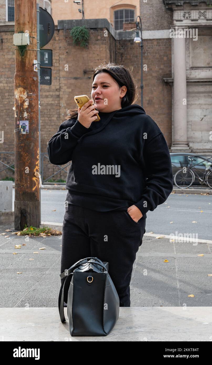 Roma, Italia - 22 ottobre 2022: Strette stradine nel centro di Roma. Ragazza che parla su un telefono cellulare Foto Stock