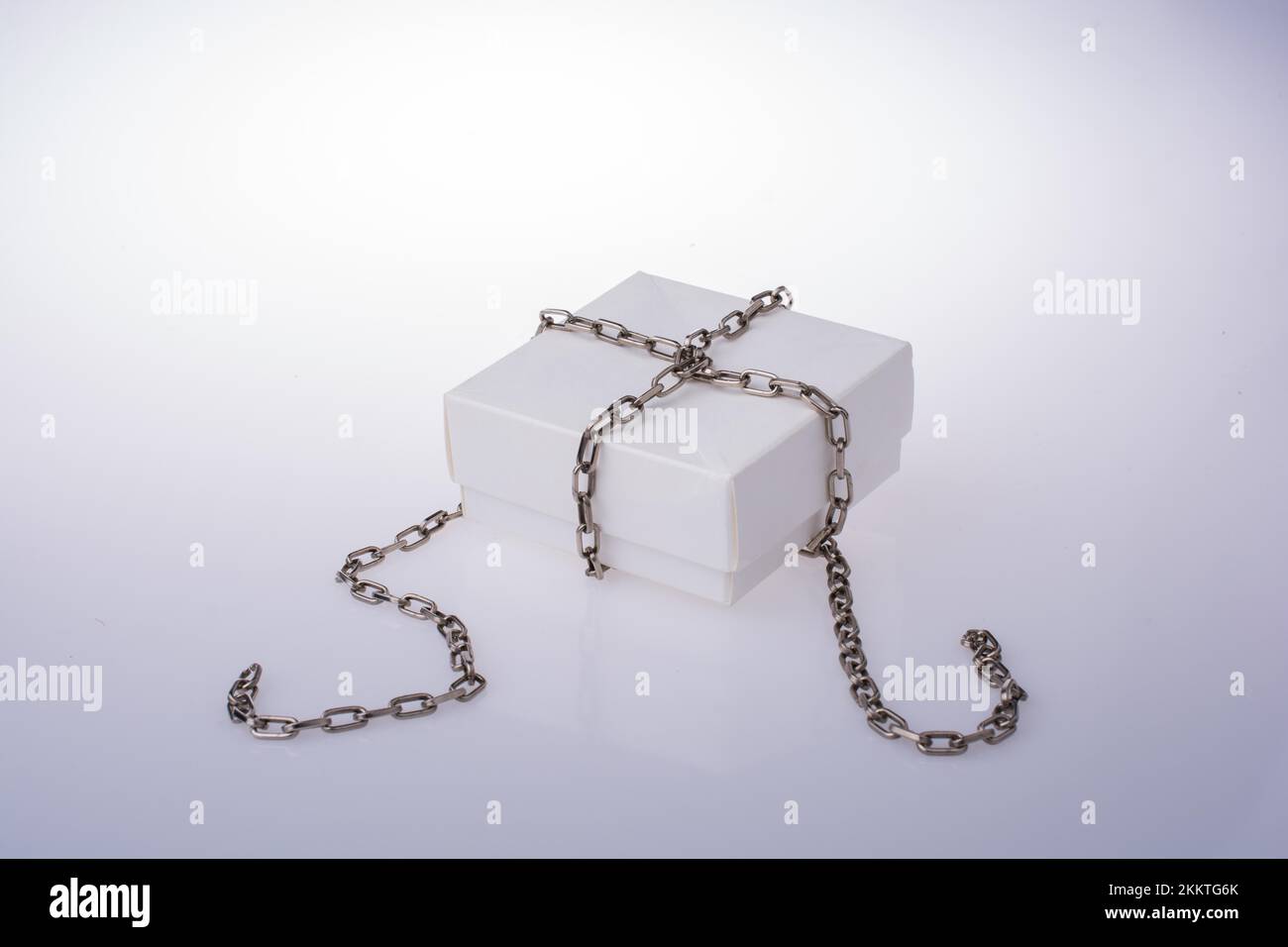 Confezione regalo con una catena attorno su sfondo bianco Foto Stock