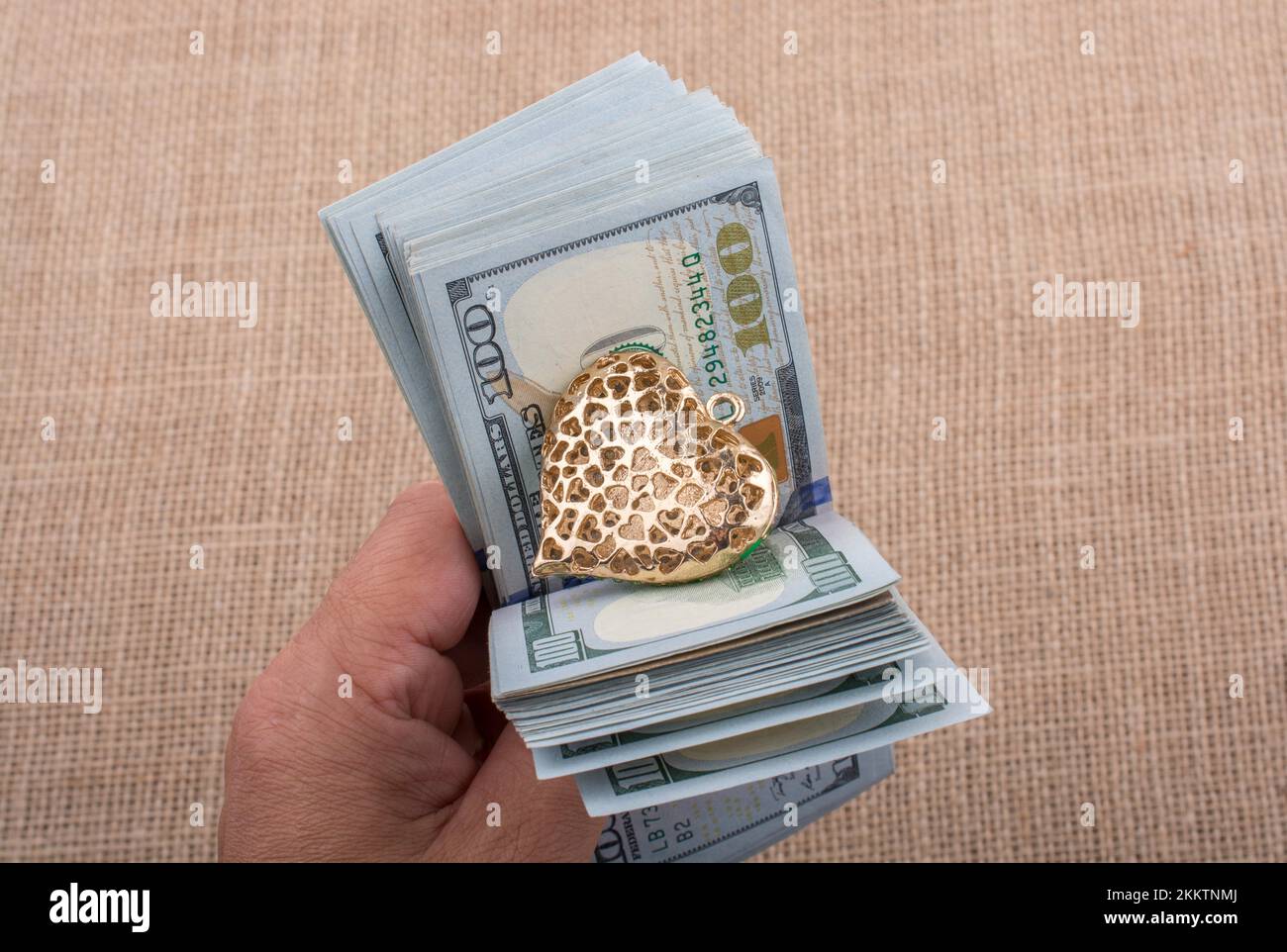 American 100 banconote di dollari con un clip di cuore in mano Foto Stock
