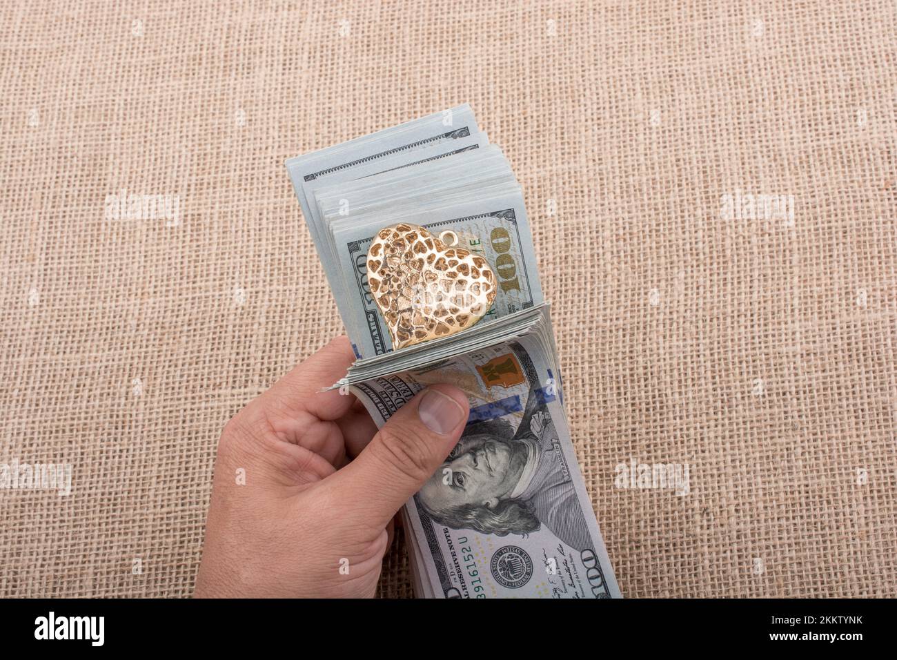 American 100 banconote di dollari con un clip di cuore in mano Foto Stock