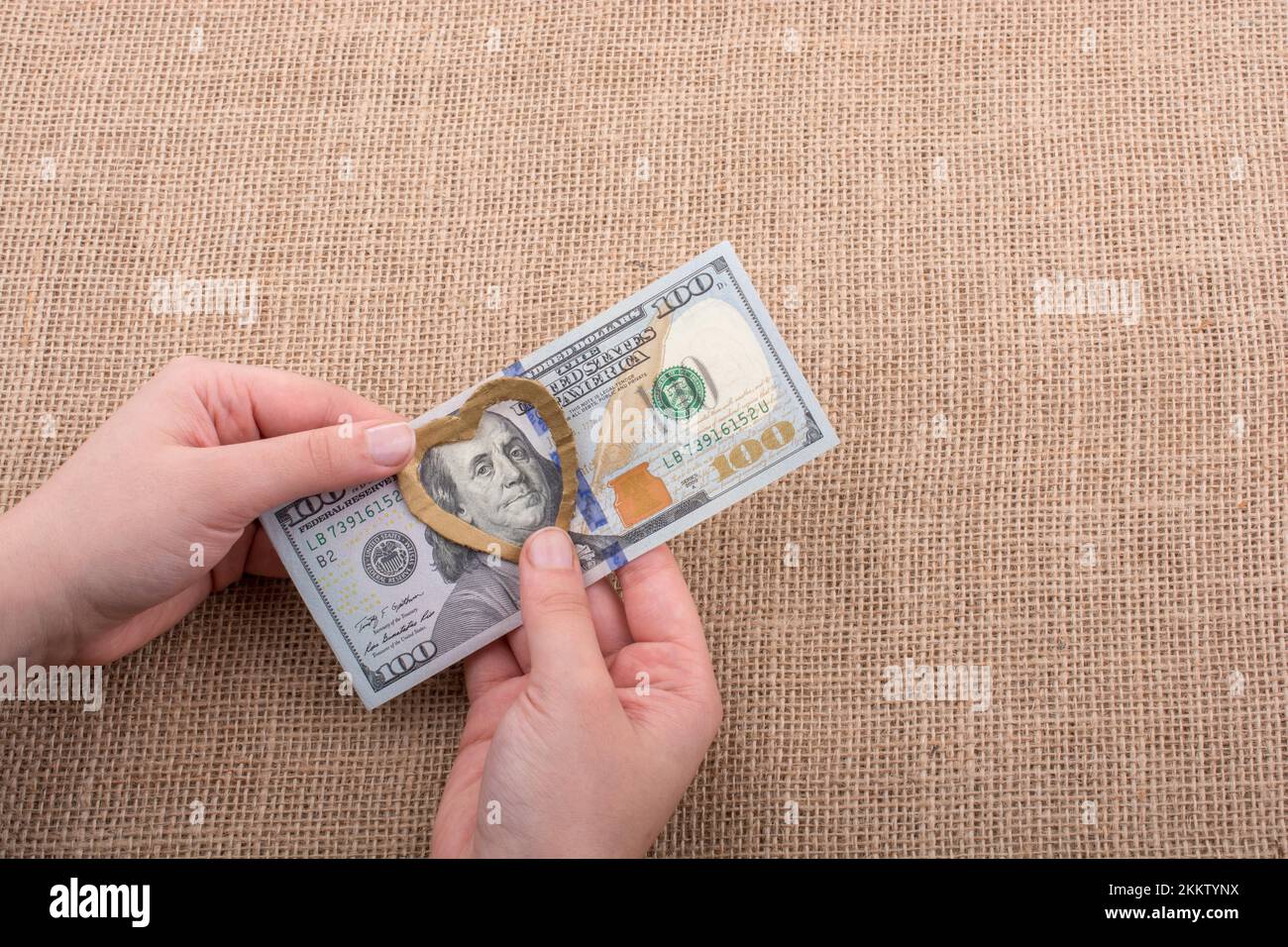 American 100 banconote di dollari con un clip di cuore in mano Foto Stock