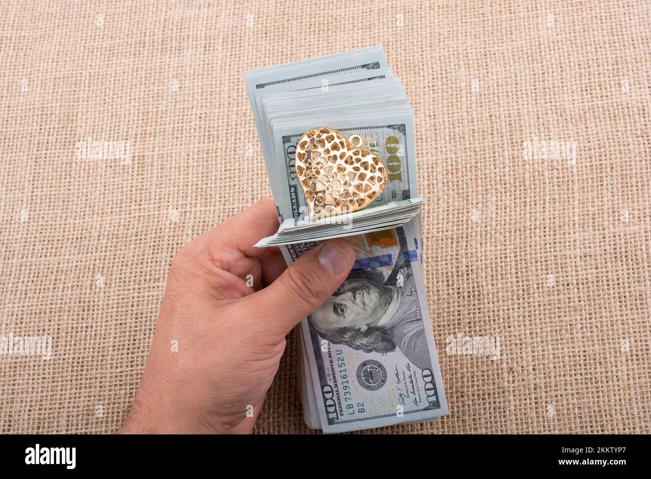 American 100 banconote di dollari con un clip di cuore in mano Foto Stock