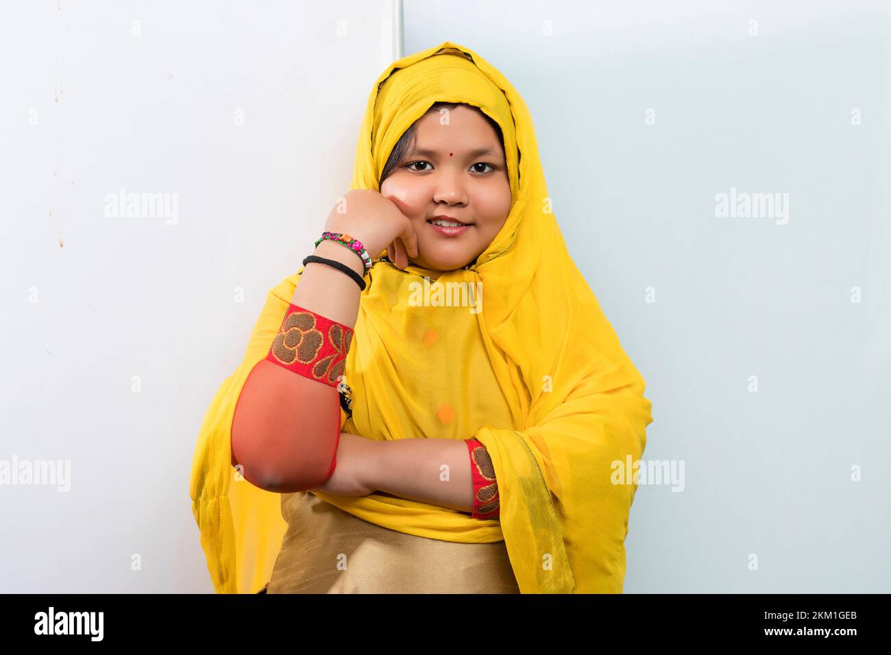 Ragazza musulmana con mano sul mento contro sfondo grigio Foto Stock