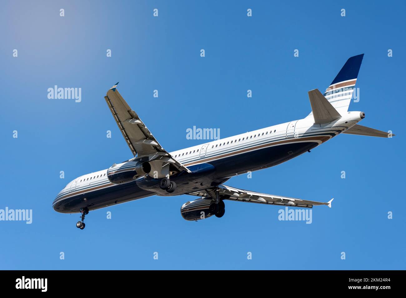 Dal basso di un moderno aereo bianco con strisce blu sotto un cielo nuvoloso e luminoso nelle giornate di sole Foto Stock