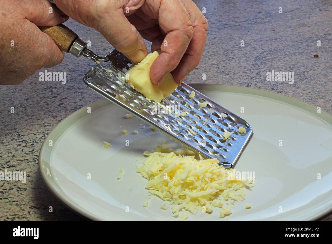 Grattugiare a mano il formaggio con una grattugia su un piatto Foto stock -  Alamy