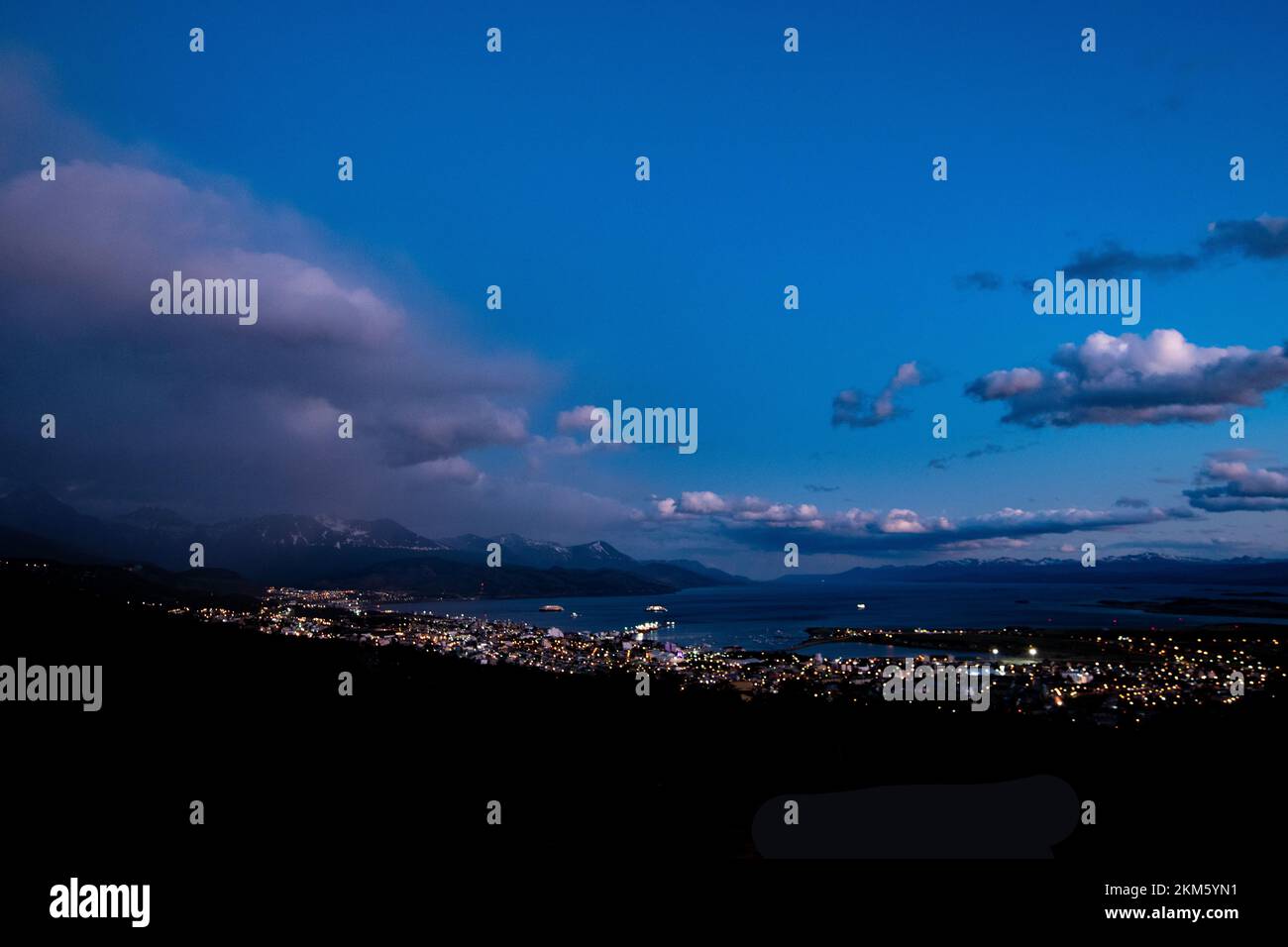 La città di Ushuaia, Argentina, di notte, dove il porto incontra la città e le montagne sullo sfondo. Foto Stock