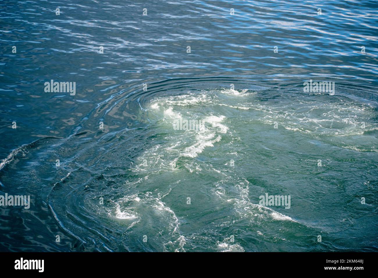 Il motore della barca sta riaccendendo l'acqua dell'oceano creando e turbolento sfondo. Foto Stock