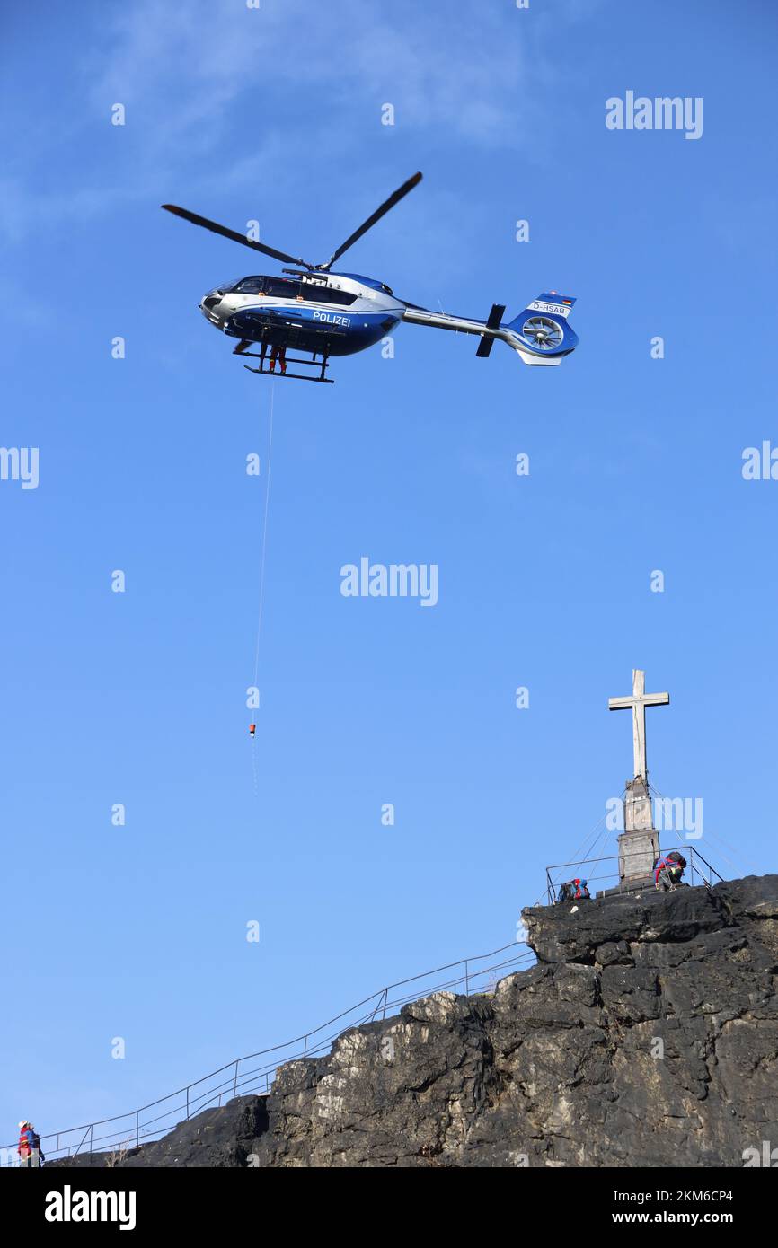 Ballenstedt, Germania. 26th Nov 2022. Un elicottero di polizia abbassa un membro della squadra di salvataggio di montagna Harz sopra il massiccio di montagna sul Gegensteinen utilizzando un verricello a cavo. I 20 membri di Bergwacht, addestrati al salvataggio aereo, devono mettere regolarmente in pratica le loro conoscenze teoriche. In totale, questo è il quarto giorno di esercizio con la polizia. Credit: Matthias Bein/dpa/Alamy Live News Foto Stock