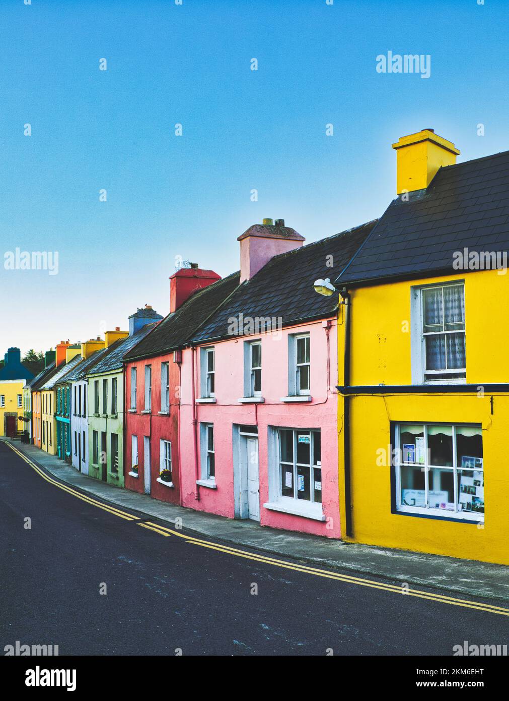 Fila di vivaci case dipinte in modo luminoso all'alba nel villaggio di Eyeries, Penisola di Beara, Contea di Cork, Irlanda Foto Stock