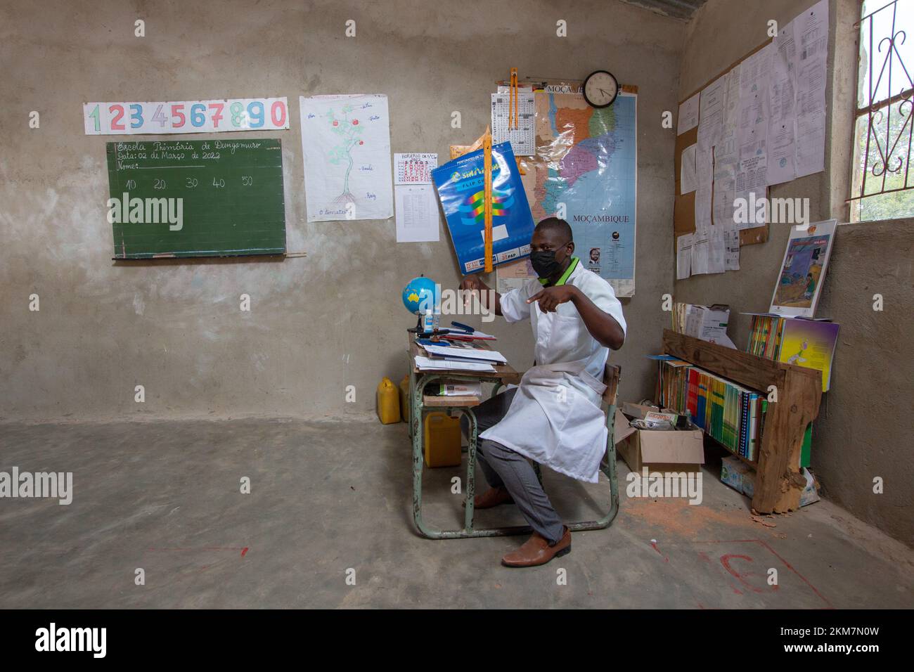 Insegnante in una stanza con materiale didattico e con un cappotto bianco Foto Stock