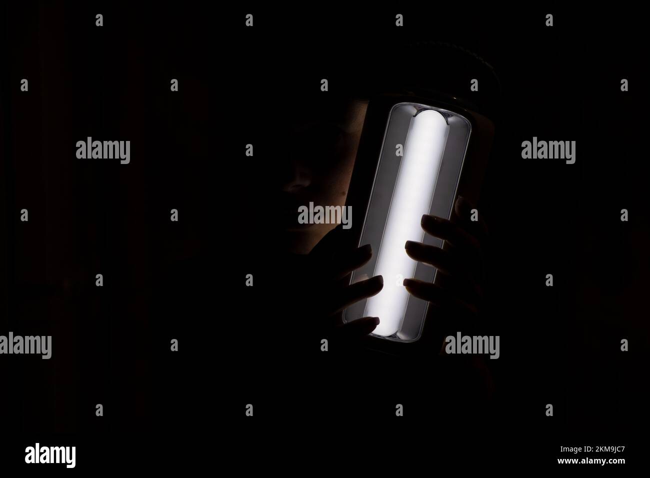 Ragazza Ucraina con una torcia a LED su una batteria al buio a casa senza luce dopo attacchi razzo contro l'Ucraina senza luce, guerra in Ucraina, Ukr Foto Stock