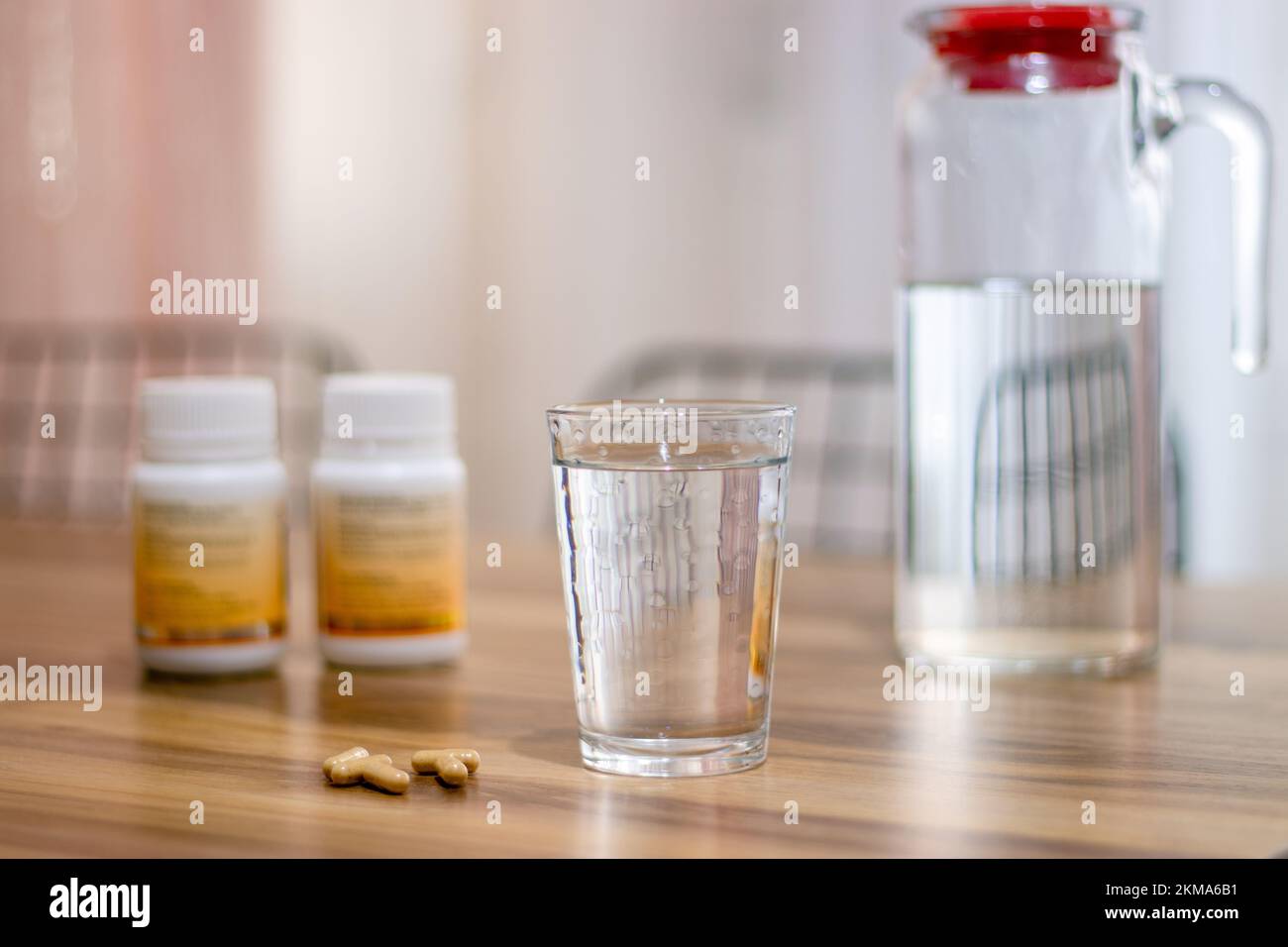 Pillola capsula medicina e vetro di acqua su sfondo di legno. Vista laterale..fuoco selettivo. Foto Stock