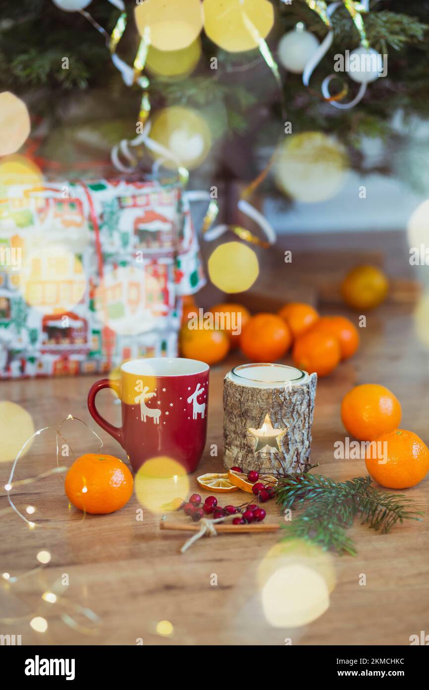 Tazza, candelabro e frutta vicino all'albero di Natale Foto Stock