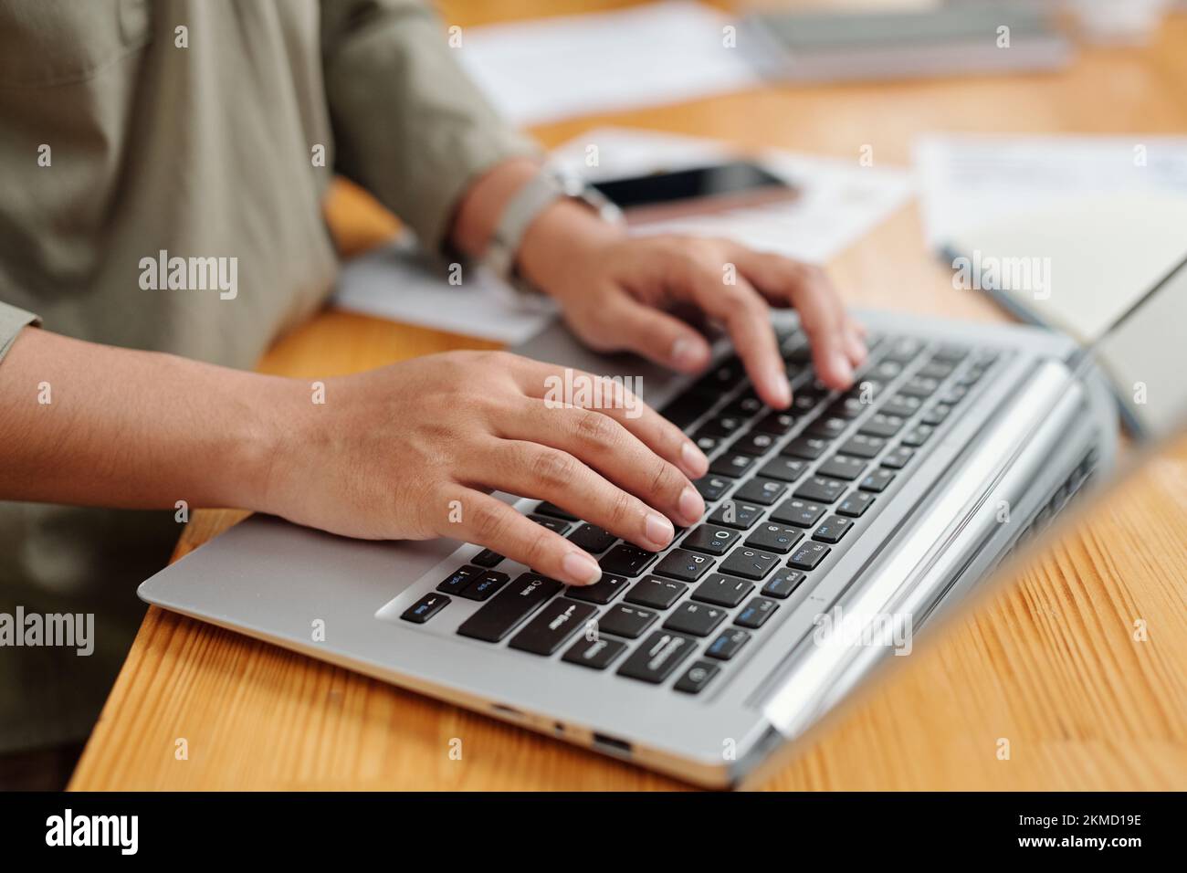 Attenzione selettiva alla mano destra della giovane dipendente e alla tastiera del laptop durante la comunicazione online o la rete per posto di lavoro Foto Stock