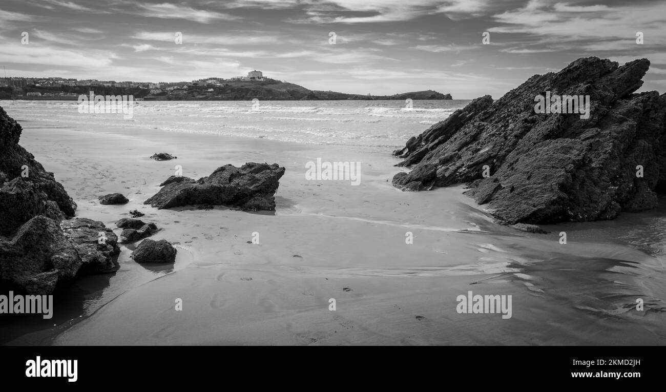 Rocce nella sabbia di Towan Beach con vista sul porto, il promontorio e il centro di Newquay sullo sfondo Foto Stock