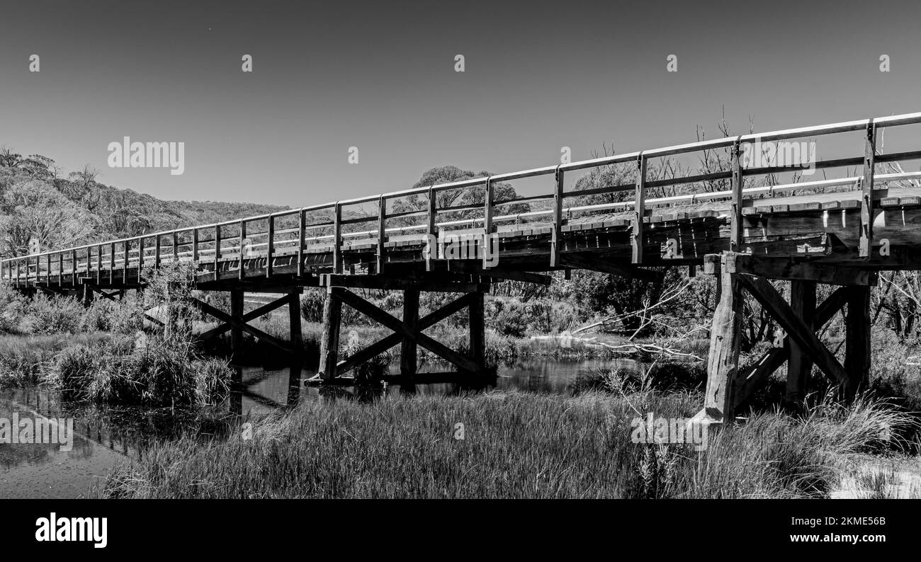 Un vecchio ponte di legno che attraversa un fiume nelle Alpi australiane Foto Stock