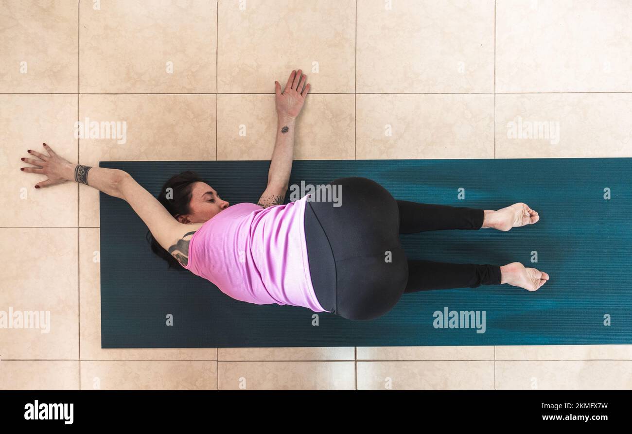 vista dall'alto di una donna con tatuaggi che pratica yoga in posizione parsva balasana Foto Stock