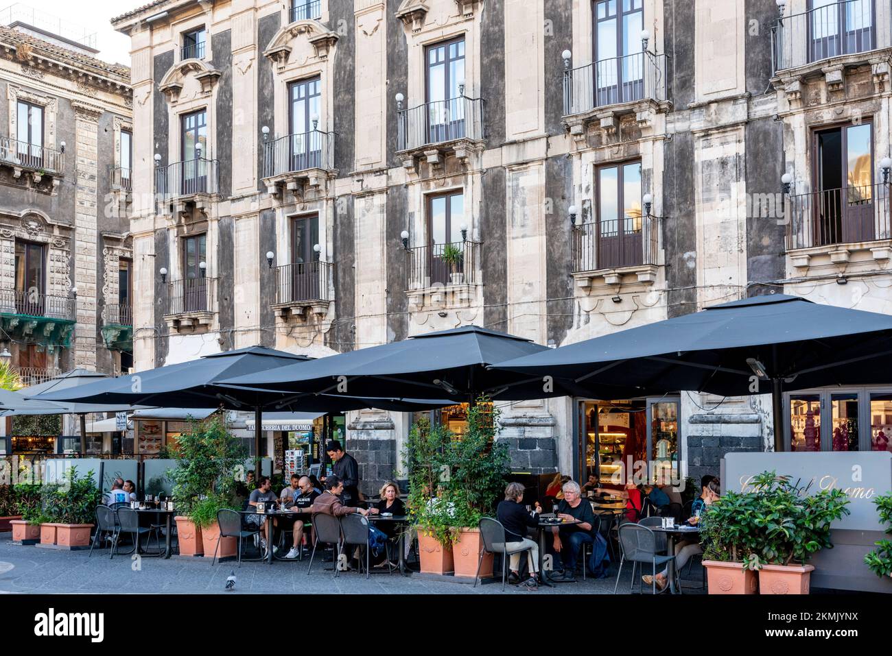 Persone sedute presso un caffè/ristorante all'aperto in Piazza del Duomo, Catania, Sicilia, Italia. Foto Stock