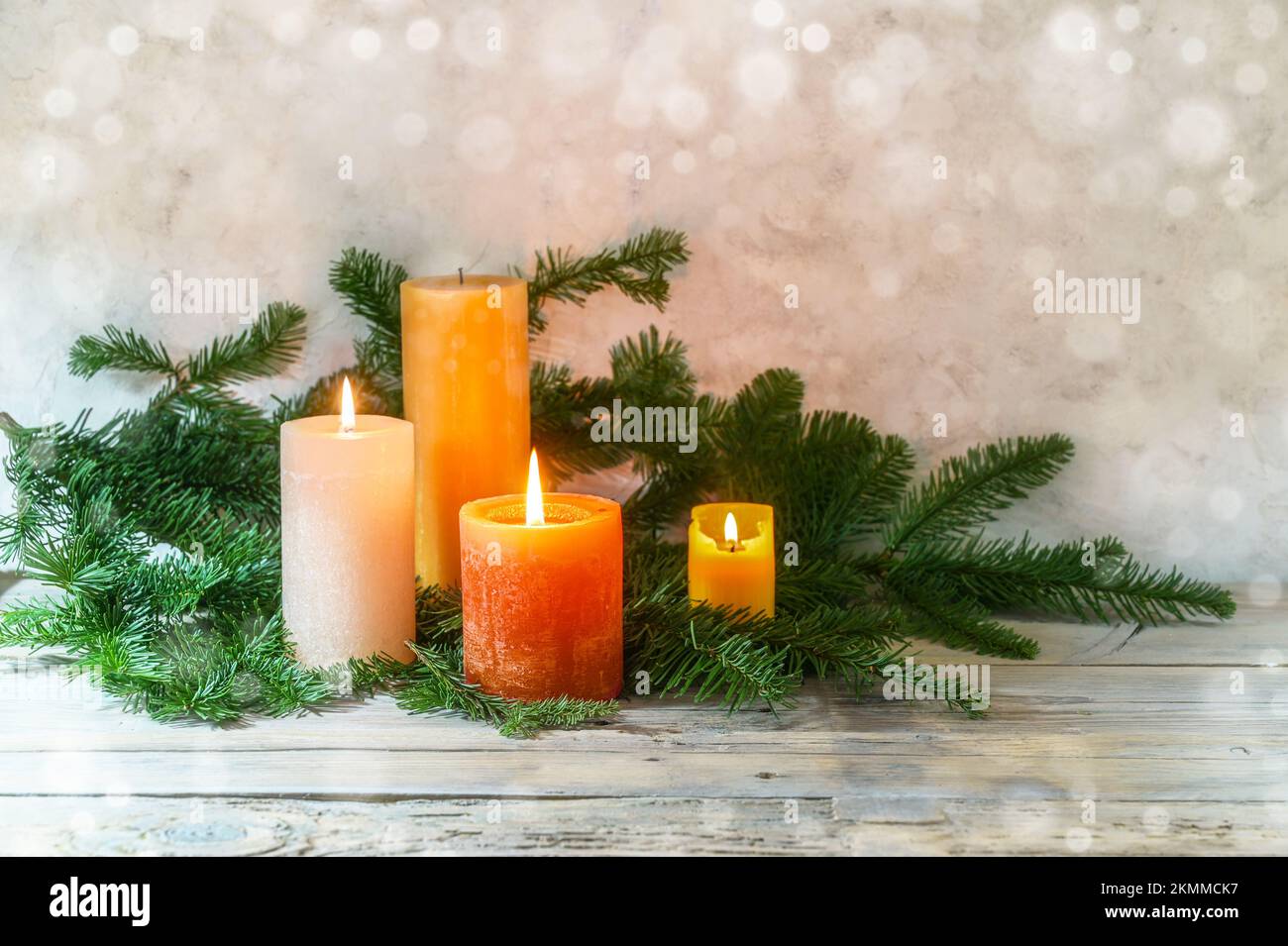 Terzo Avvento, sistemazione con quattro candele in arancione e giallo, tre sono accese con una fiamma, rami di abete su legno rustico chiaro, fondo bokeh, poliziotto Foto Stock