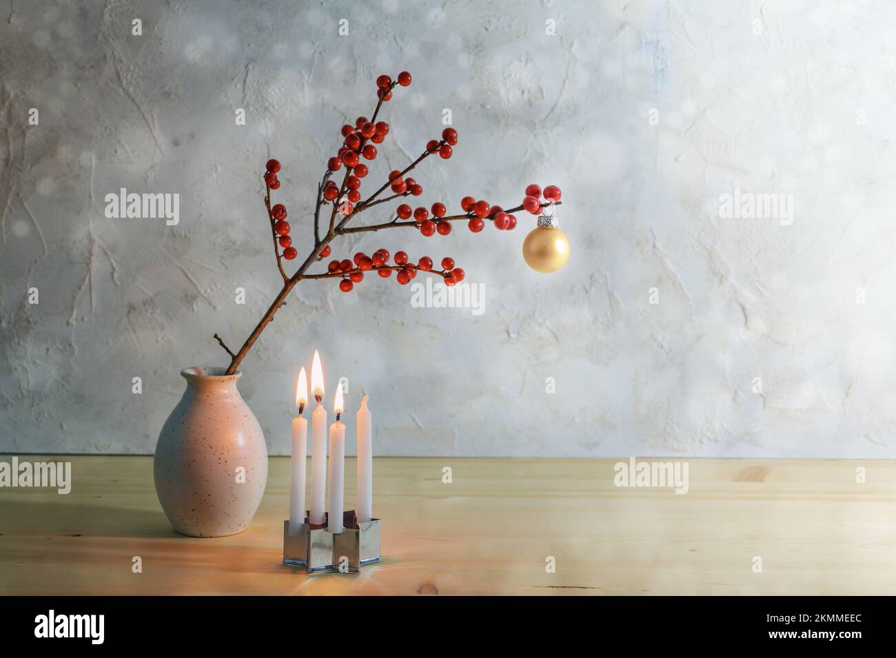 Terzo avvento minimalista con quattro piccole candele, tre bruciano e un ramo di bacca con una palla di natale in un vaso, sfondo innevato con co Foto Stock