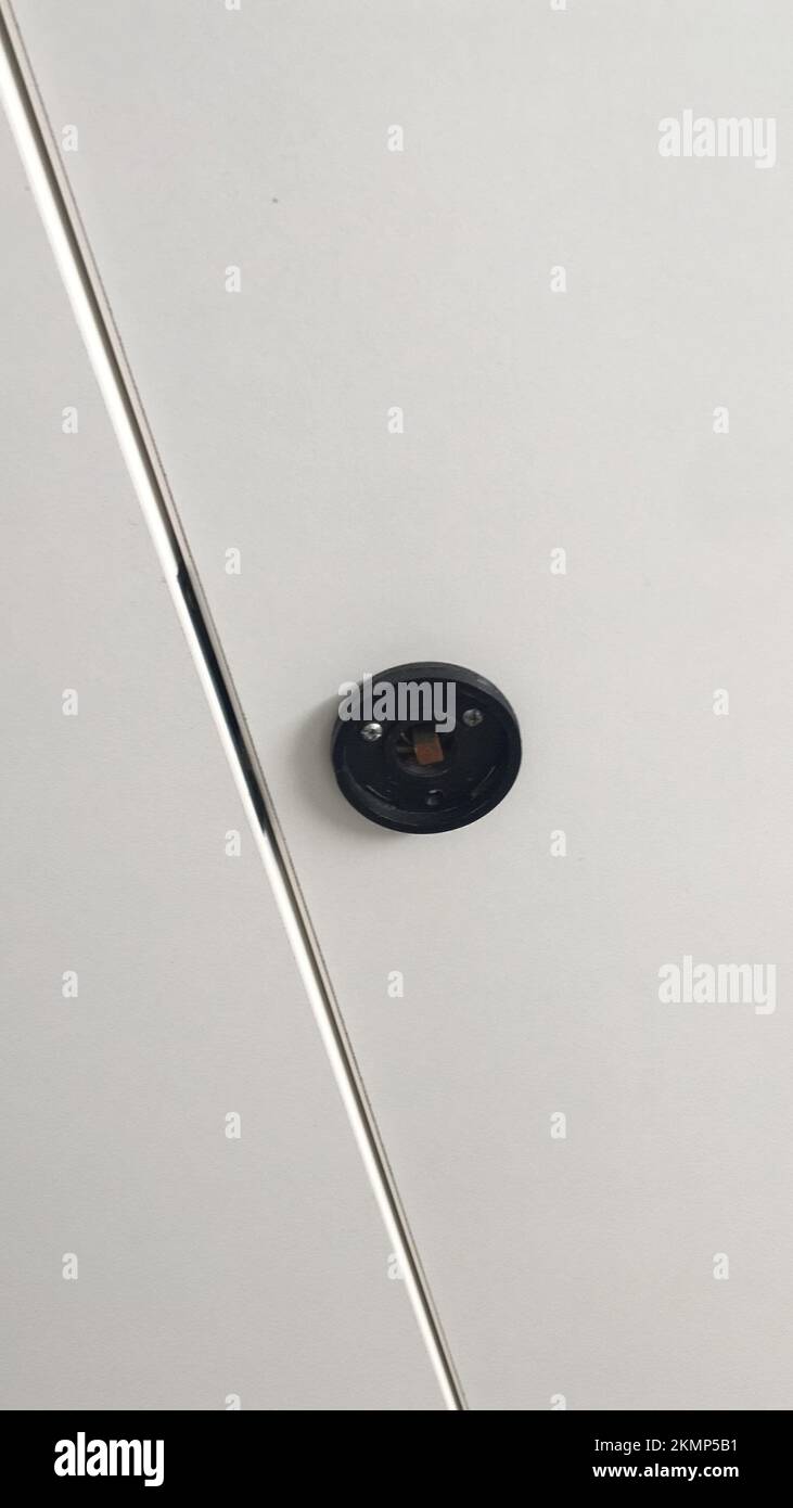 Primo piano astratto e alto che mostra una ringhiera in metallo lucido e un supporto rotondo nero su una parete bianca. Foto Stock