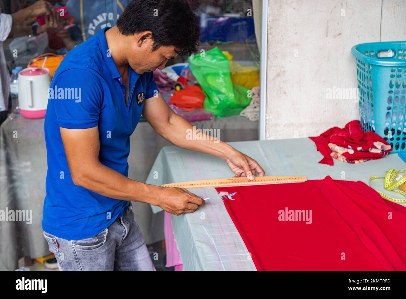 Ho Chi Minh City, Vietnam - 8 novembre 2022: In un piccolo negozio di sarto a Saigon. Un uomo segna il tessuto per fare un abito tradizionale ao dai, il traditio Foto Stock