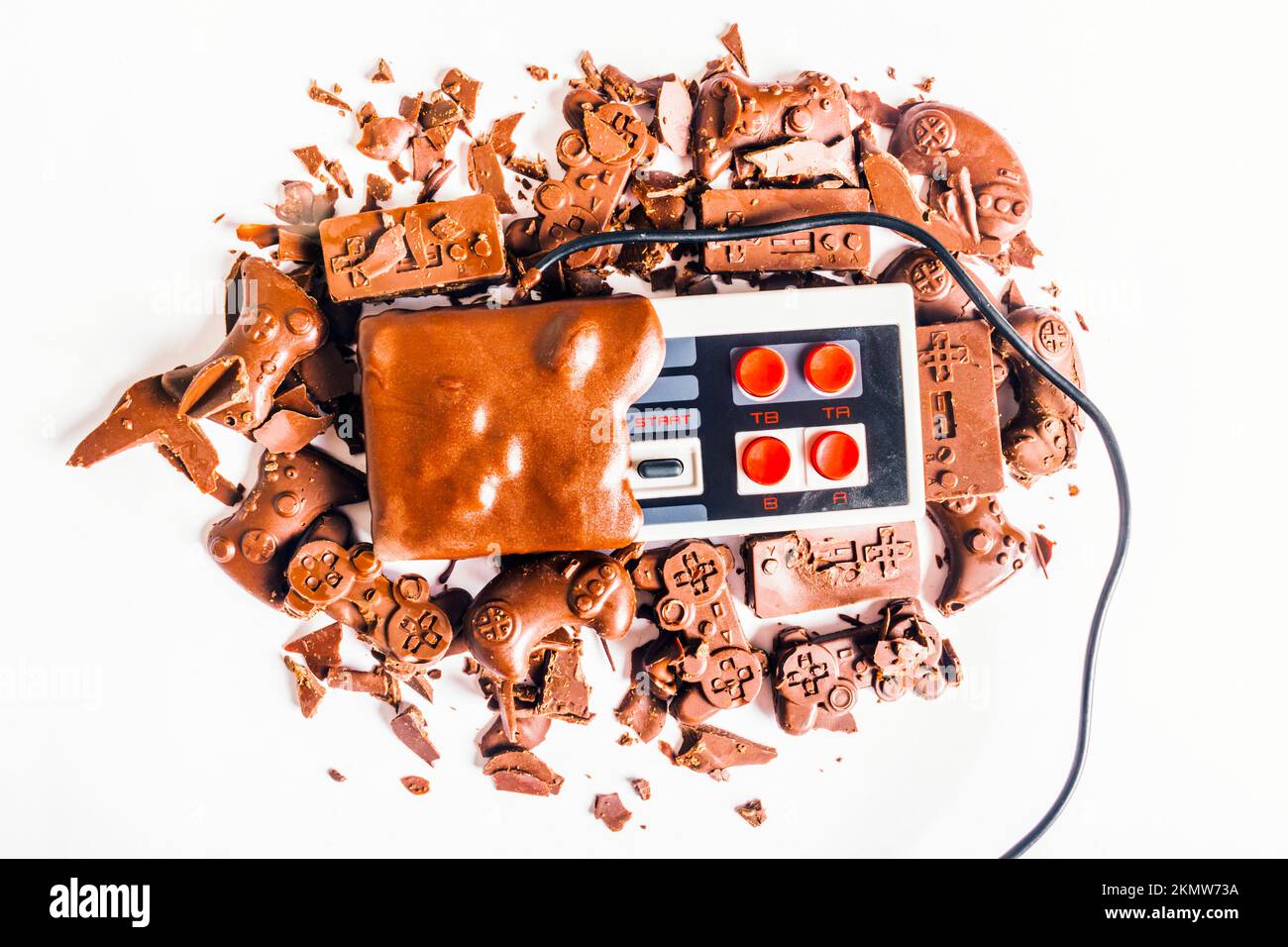 Still life art su un joypad di cacao divertimento con console nestalgiche e cioccolato byte Foto Stock