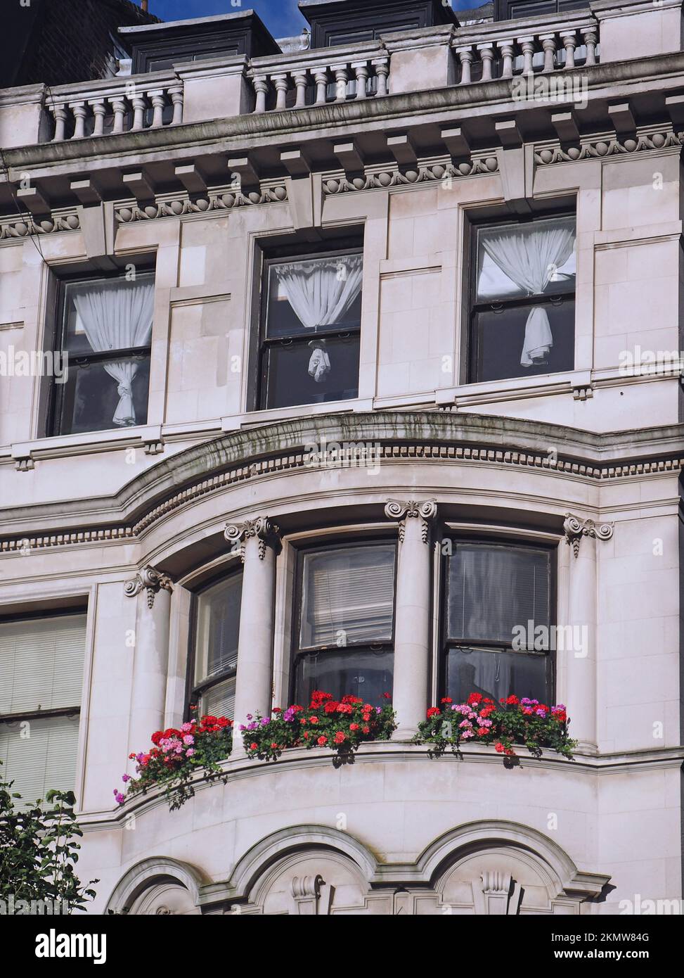 Edificio di appartamenti in vecchio stile barocco con fiori colorati in una finestra a bovindo Foto Stock
