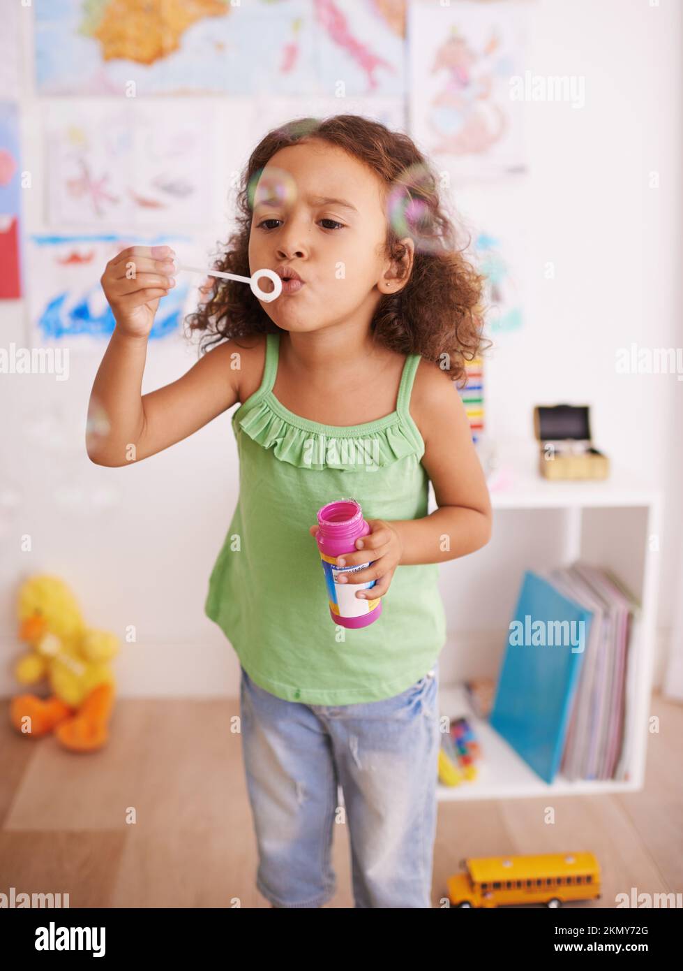 Bubblicious divertimento. Una bambina adorabile che soffia bolle nella sua camera da letto. Foto Stock