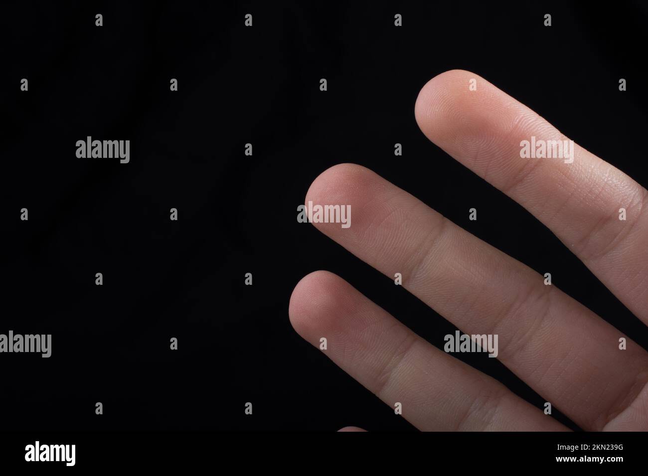 Tre dita di una mano del bambino in parte visibile in sfondo nero Foto Stock