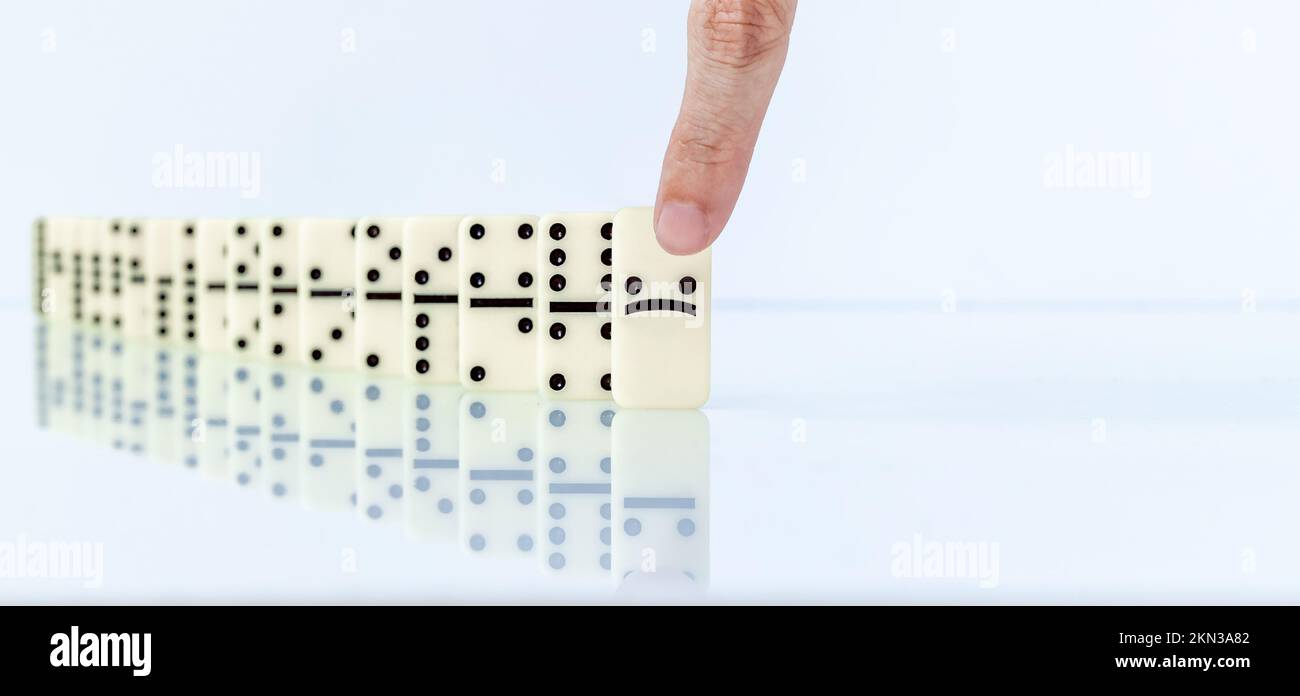 Dito umano che inizia l'effetto domino su sfondo bianco. Foto Stock