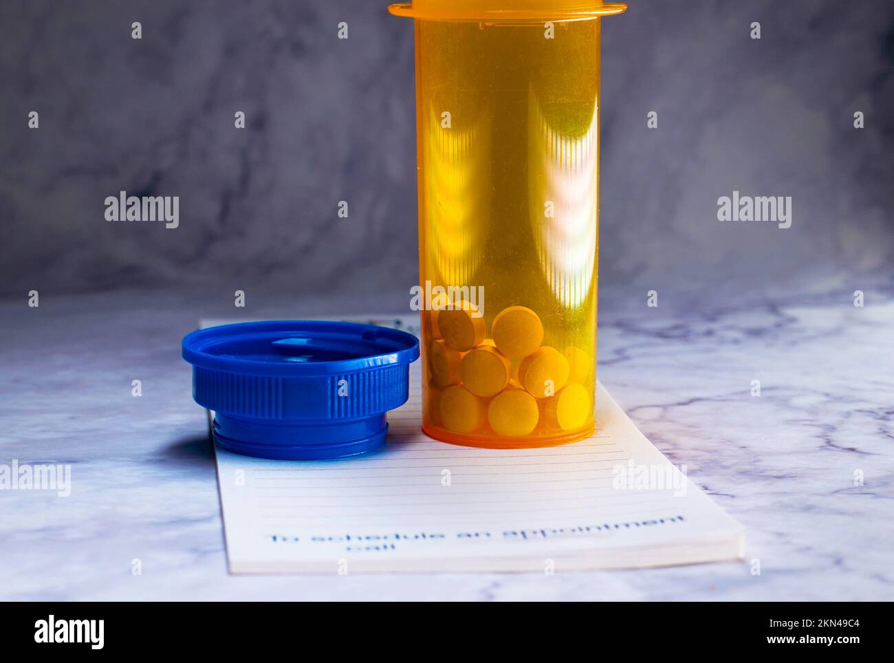 Aprire il flacone del medicinale con le pillole per qualcuno. sulla parte superiore di un pad di prescrizione Foto Stock